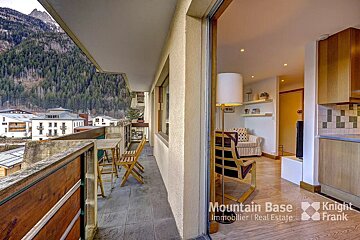 A balcony with a table and chairs and a sign that says mountain base