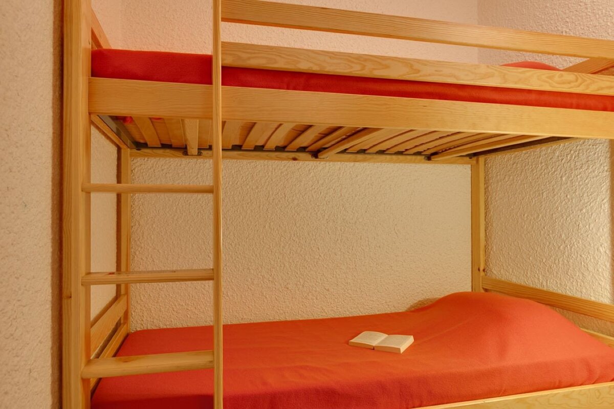 A bunk bed with red sheets and a book on it
