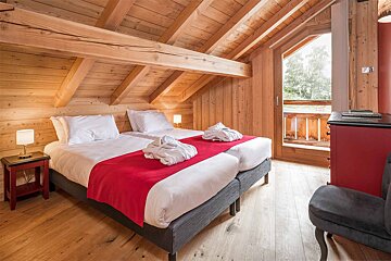 A bedroom with two beds and a red chair