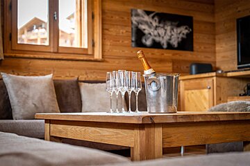 A bottle of champagne sits in an ice bucket on a wooden table