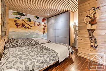 A bedroom with twin beds featuring wood paneling, a ceiling with wood slats, and artwork of women on the walls.