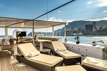 A yacht deck with lounge chairs and a table