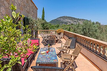 A balcony with a table and chairs and a mountain in the background