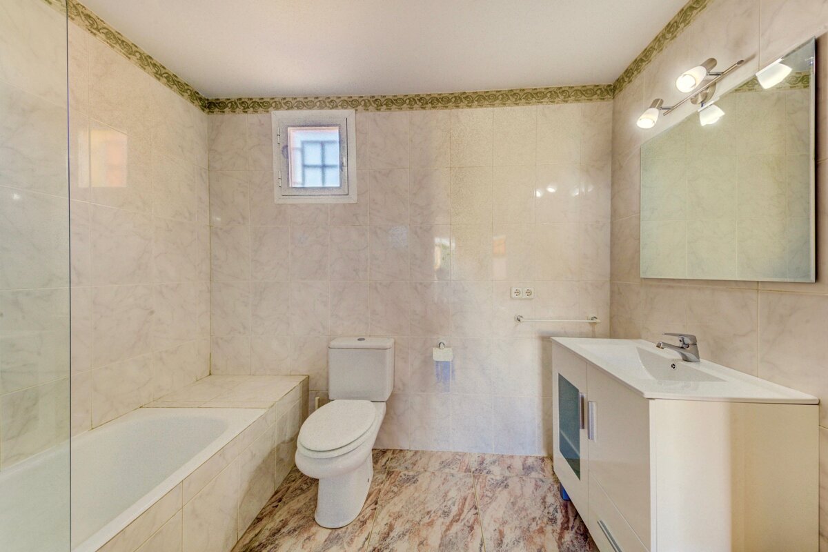 A bathroom with a toilet a sink and a window