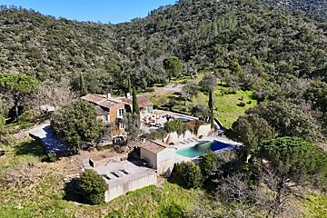 An aerial view of a house surrounded by trees and a large pool