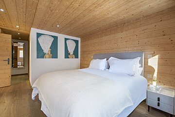 A bedroom with a bed and two paintings on the wall
