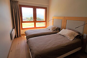 A bedroom with two beds and a large window