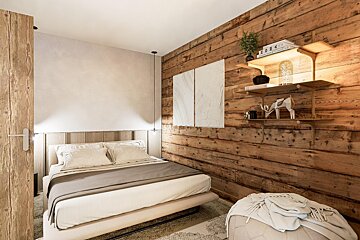 A bedroom with a wooden wall and a bed