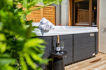 A bottle of champagne sits on a table next to a hot tub