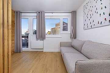 A living room with a couch and a painting of skiers on the wall