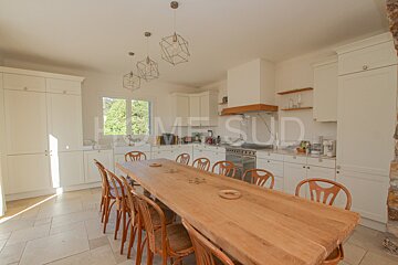 A kitchen with a long wooden table and chairs and a sign that says home sud
