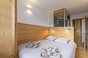 A bedroom with a wooden headboard and two towels on the bed