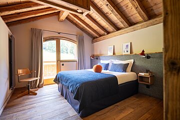 A bedroom with a large bed and a chair