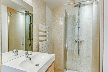 A bathroom with a walk in shower and a sink