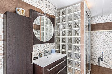 A bathroom with a sink and a mirror surrounded by glass blocks