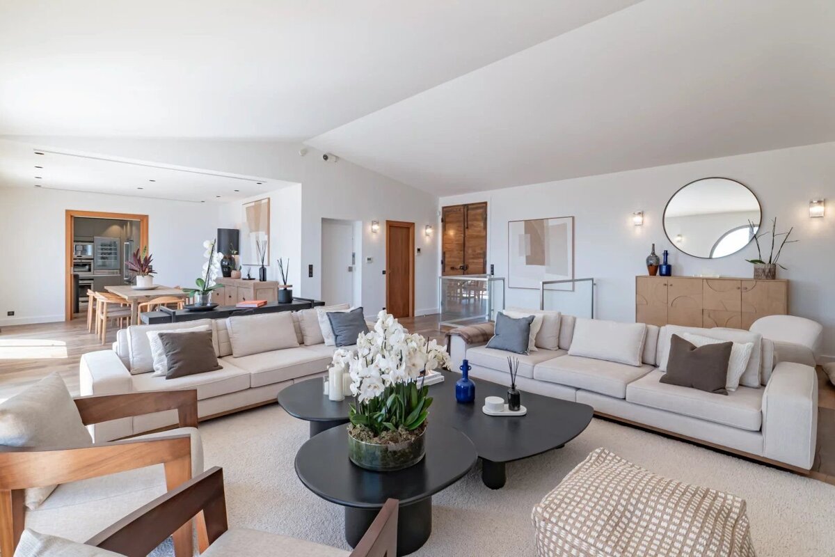 Bright, modern living room featuring off-white sofas, black coffee tables with white orchids, and elegant minimalist decor.