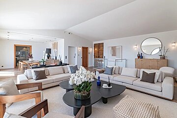 Bright, modern living room featuring off-white sofas, black coffee tables with white orchids, and elegant minimalist decor.