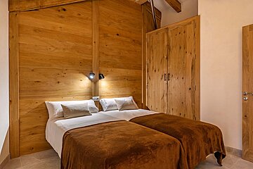 A bedroom with two beds and a wooden wall