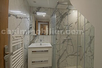 A bathroom with marble walls and a website called chximmobilier.com