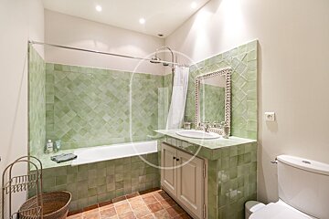 A bathroom with green tiles and a toilet