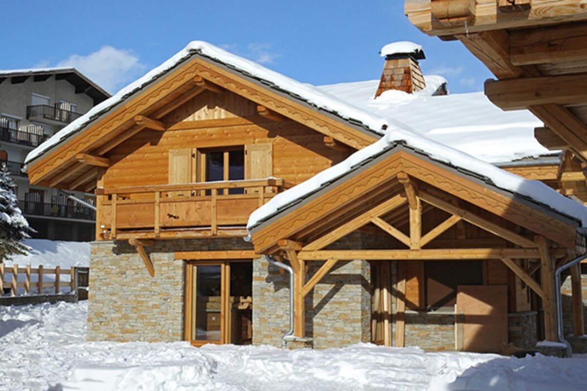 A wooden house with snow on the roof and a balcony