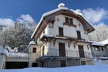 A white house with a balcony is covered in snow