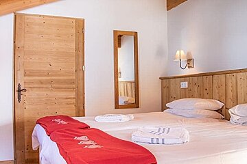 A bedroom with two beds and a mirror