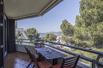 A balcony with a table and chairs overlooking the ocean