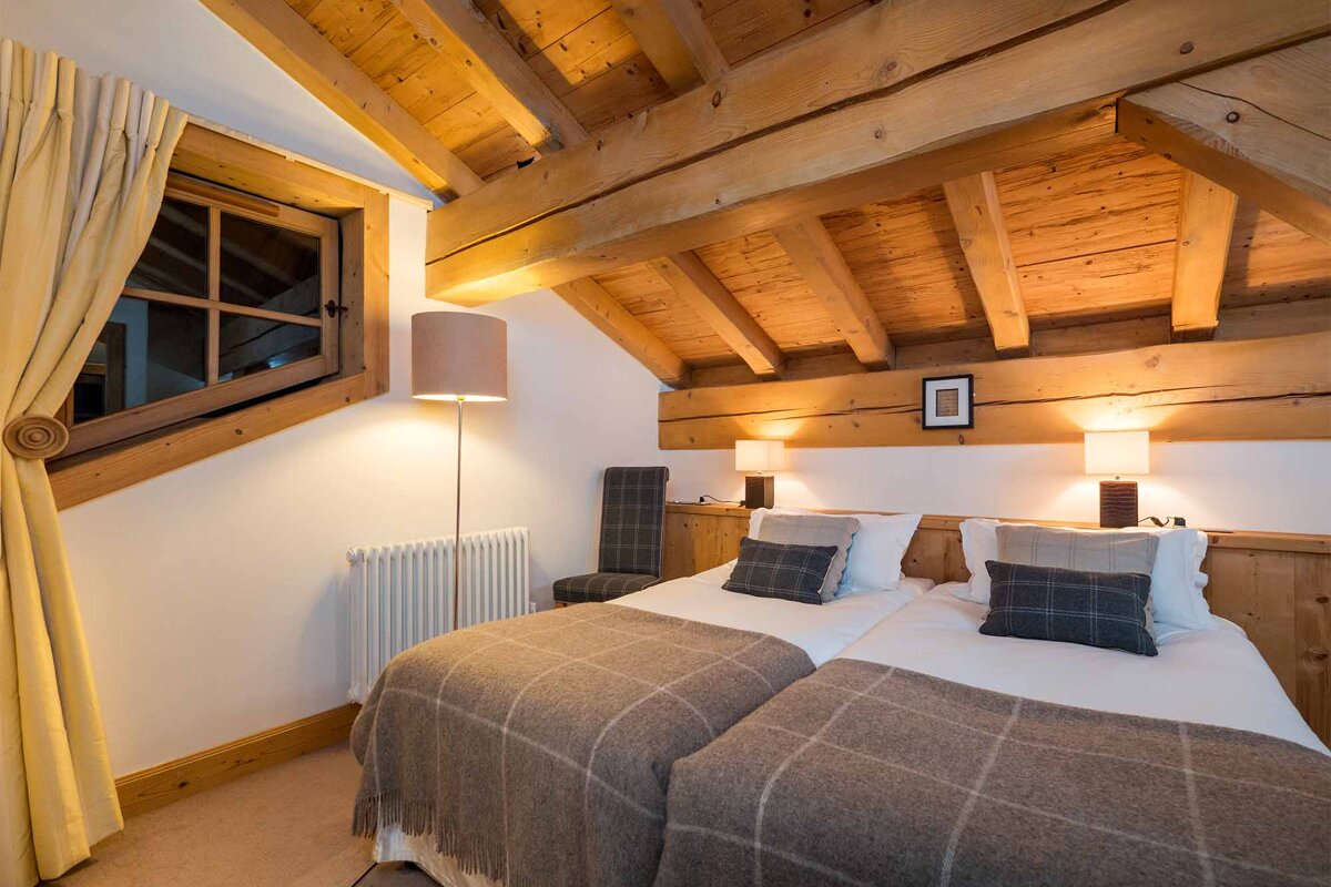 A bedroom with two beds and a wooden ceiling