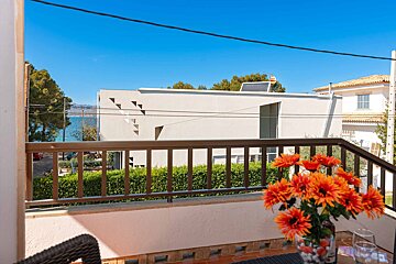 A balcony with flowers and a view of the ocean