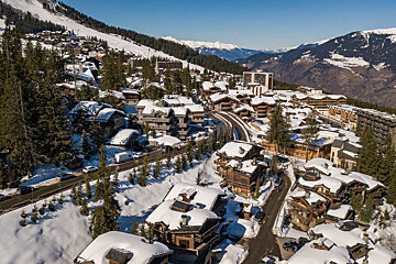 An aerial view of a snow covered village with mountains in the background