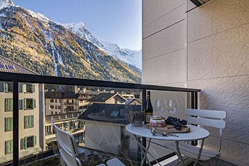 A balcony with a bottle of wine and two glasses on it