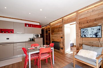 A kitchen with red chairs and a tv on the wall