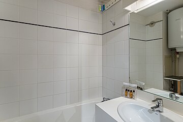 A bathroom with a bathtub sink and mirror