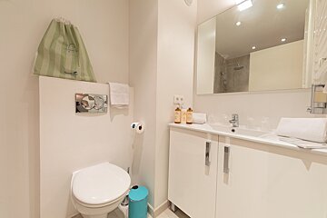 A bathroom with a toilet and a blue trash can