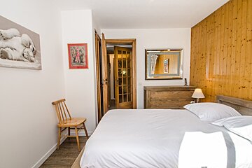 A bedroom with a large bed and a wooden chair