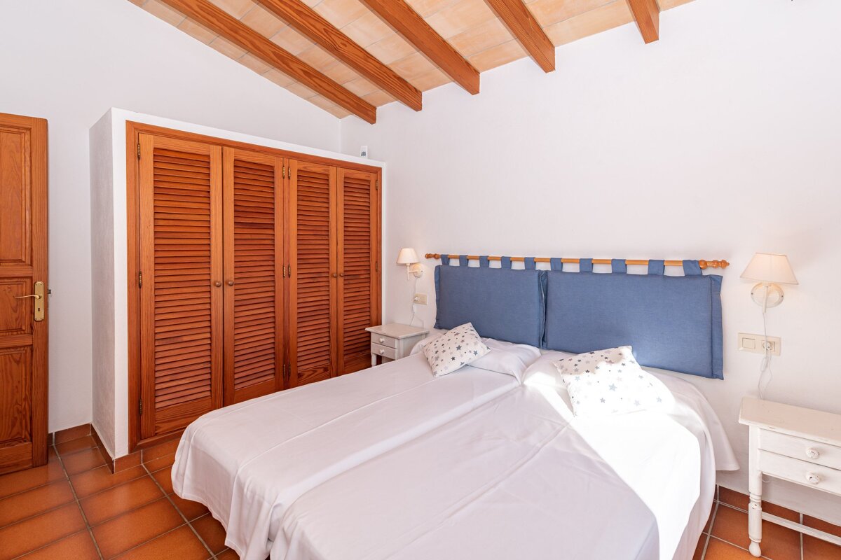 A bedroom with a blue headboard and white sheets