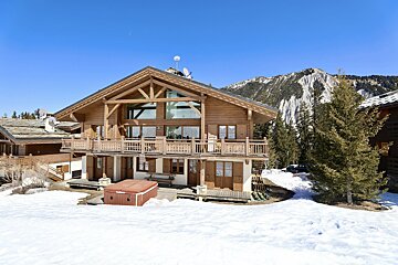 A large wooden house with a mountain in the background
