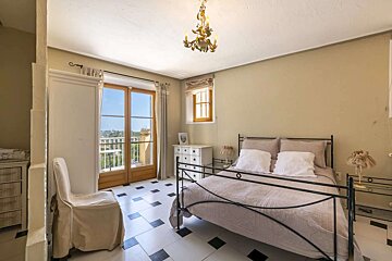 A bedroom with a wrought iron bed and a chandelier