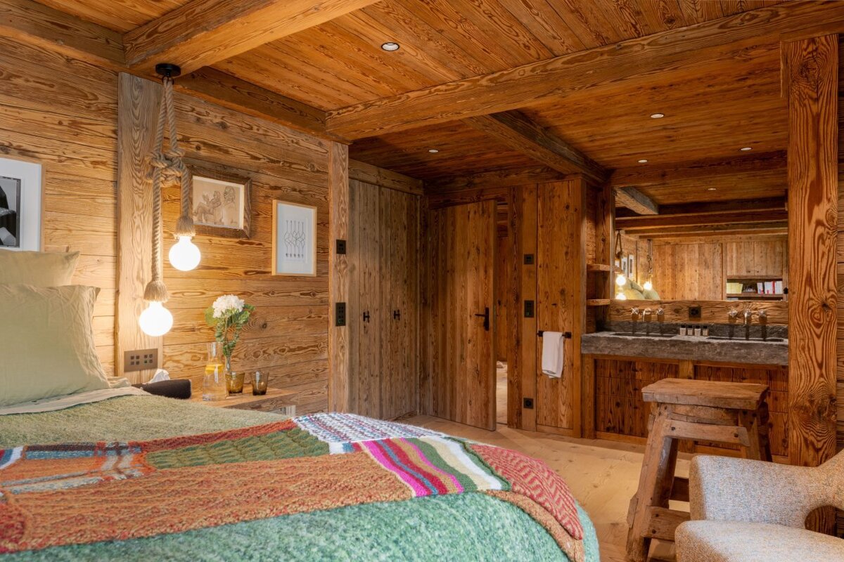 A bedroom with wooden walls and a bed with a green blanket