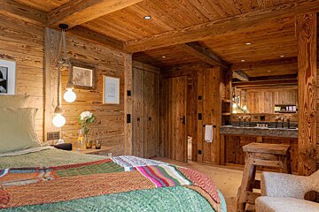 A bedroom with wooden walls and a bed with a green blanket