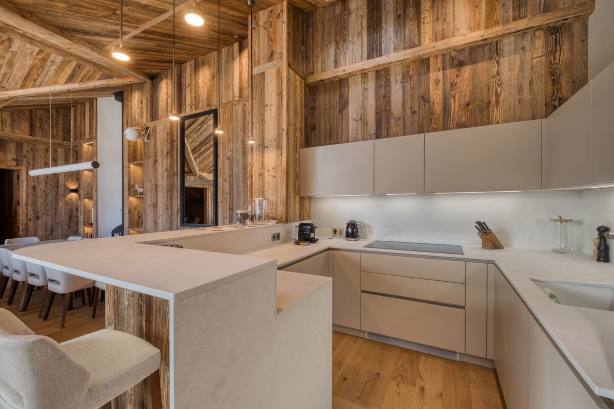 A kitchen with white cabinets and wooden walls