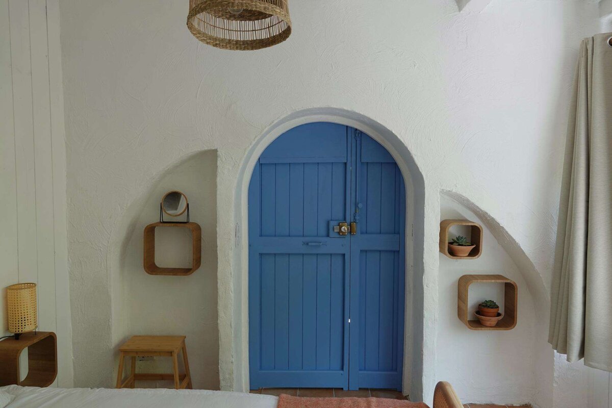 A bedroom with a blue door and shelves on the wall