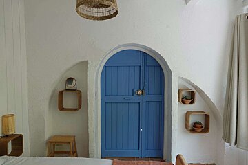 A bedroom with a blue door and shelves on the wall