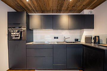A kitchen with black cabinets and a wooden ceiling