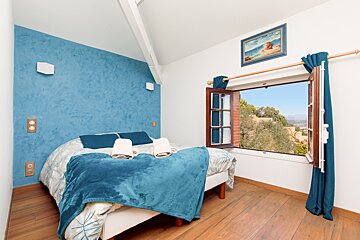 A bedroom with a blue wall and a blue blanket on the bed
