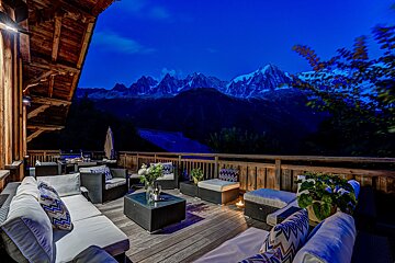 A deck with a view of the mountains at night