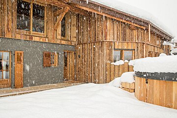 A snowy house with a hot tub in front of it