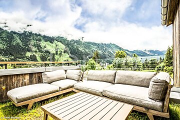 A picture of a couch and table with mountains in the background