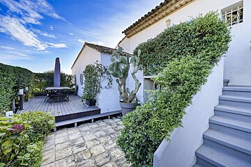 A white house with a deck and stairs leading up to it